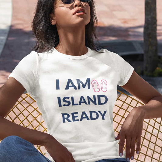 Junge Frau mit dunklem Haar und Sonnenbrille lehnt entspannt auf Stuhl, beide Arme aufgestützt. Sie trägt Crop Top mit Print.