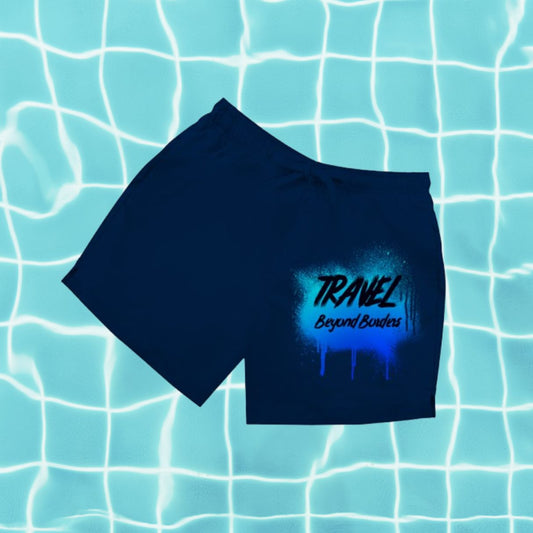 Dunkelblaue Herren Badeshorts mit Aufdruck „Travel Beyond Borders“ vor Poolwasser-Hintergrund.