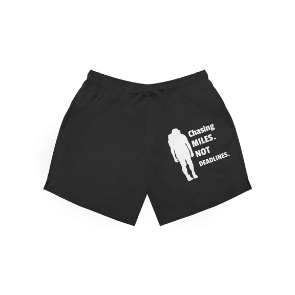 Schwarze Herren Badeshorts mit Wanderer-Silhouette und Schriftzug „Chasing Miles Not Deadlines“ in weiss.