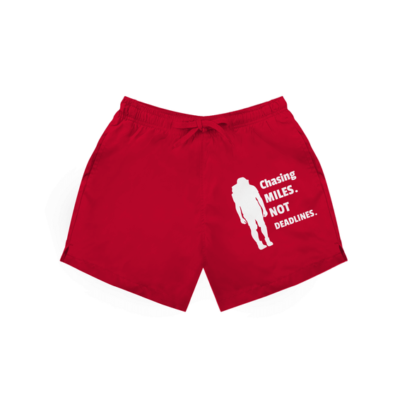 Rote Herren Badeshorts mit Wanderer-Silhouette und Schriftzug „Chasing Miles Not Deadlines“ in weiss.