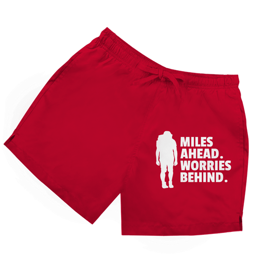 Rote Herren Badeshorts mit Wanderer-Silhouette und Schriftzug „Miles Ahead. Worries Behind.“ in weiss.