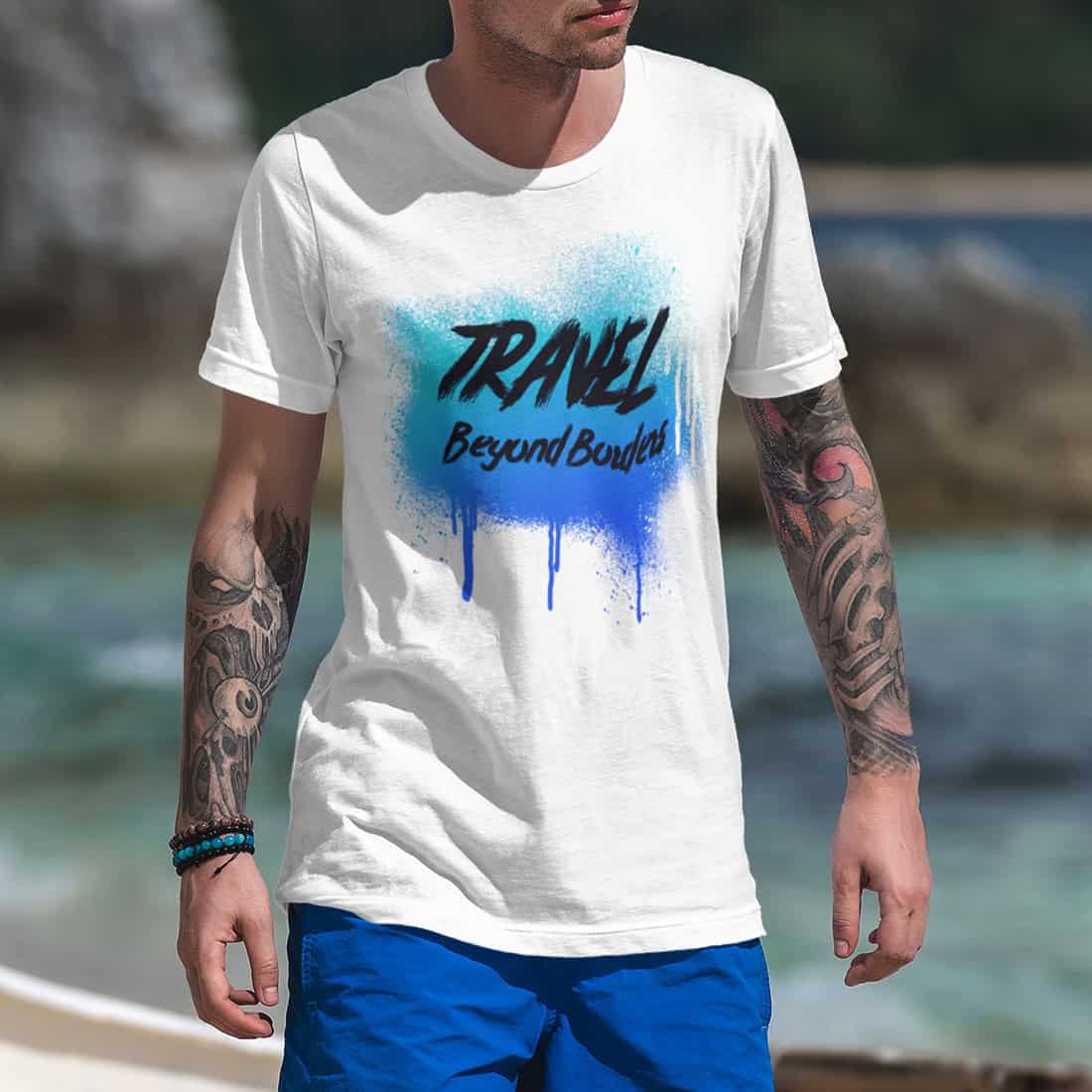 Tätowierter Mann mit blauer Shorts trägt ein weißes T-Shirt mit blauem Street-Art-Design und Spray-Effekt.