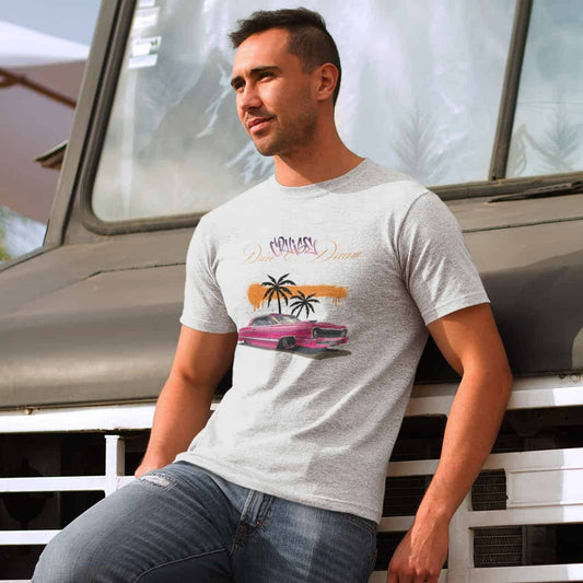 Junger Mann lehnt lässig an einem Truck. Er trägt eine zerrissene Jeans und ein helles T-Shirt mit dem markanten Design.