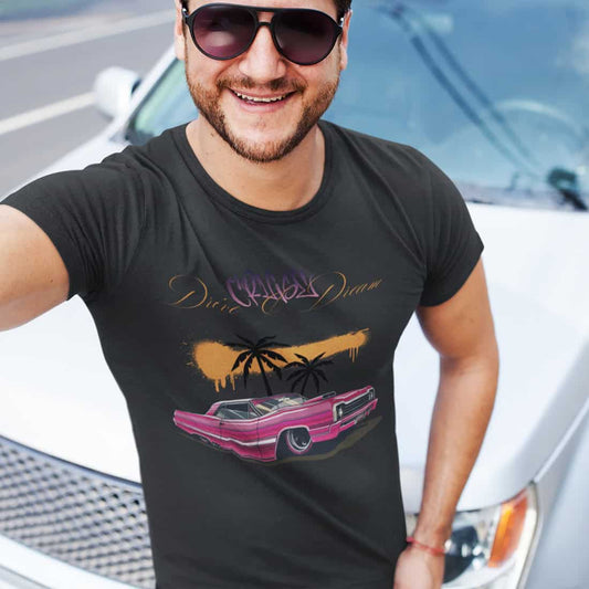 Junger Mann mit Sonnenbrille und Vollbart steht vor einem weißen Auto. Er trägt ein dunkles T-Shirt mit dem markanten Design.