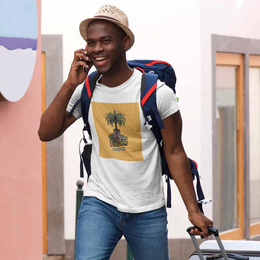 Mann mit dunkler Hautfarbe, Sonnenhut und Handy in der Hand trägt Gepäck und ein weißes T-Shirt mit dem Vacation-Design.
