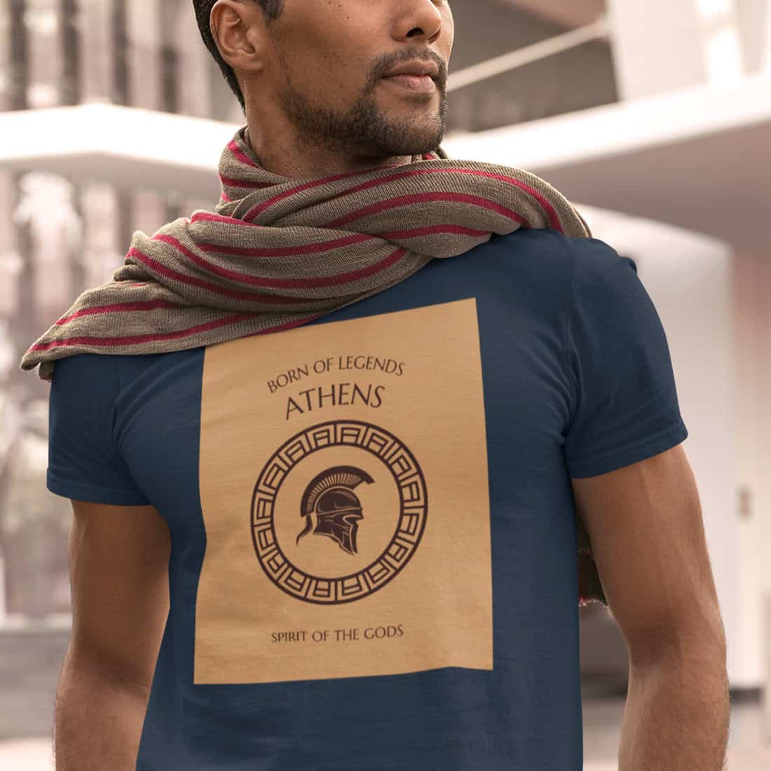 Sonnengebräunter Mann mit Bartansatz trägt einen rotgestreiften Schal auf dem GREECE ATHENS Shirt in Navy. Markantes Design.