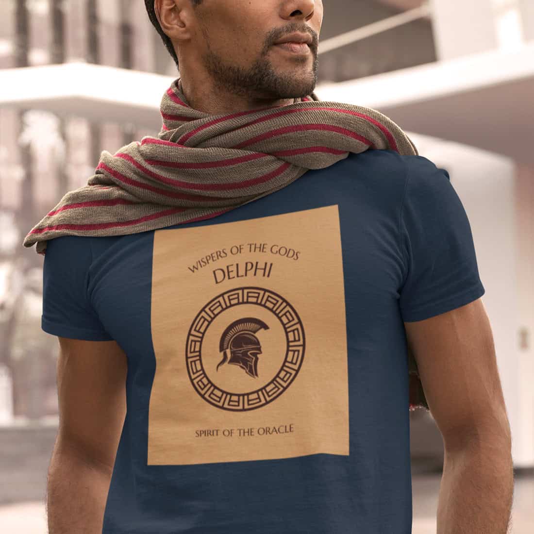 Sonnengebräunter Mann mit Bartansatz trägt einen rotgestreiften Schal auf dem GREECE DELPHI Shirt in Navy. Markantes Design.