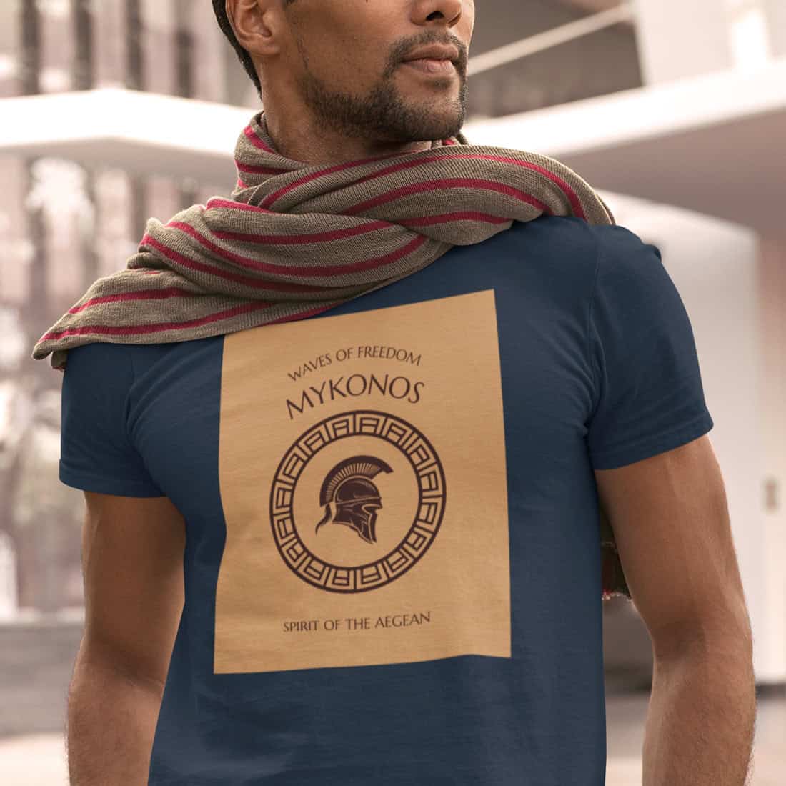 Sonnengebräunter Mann mit Bartansatz trägt einen rotgestreiften Schal auf dem MYKONOS Shirt in Navy. Markantes Design.