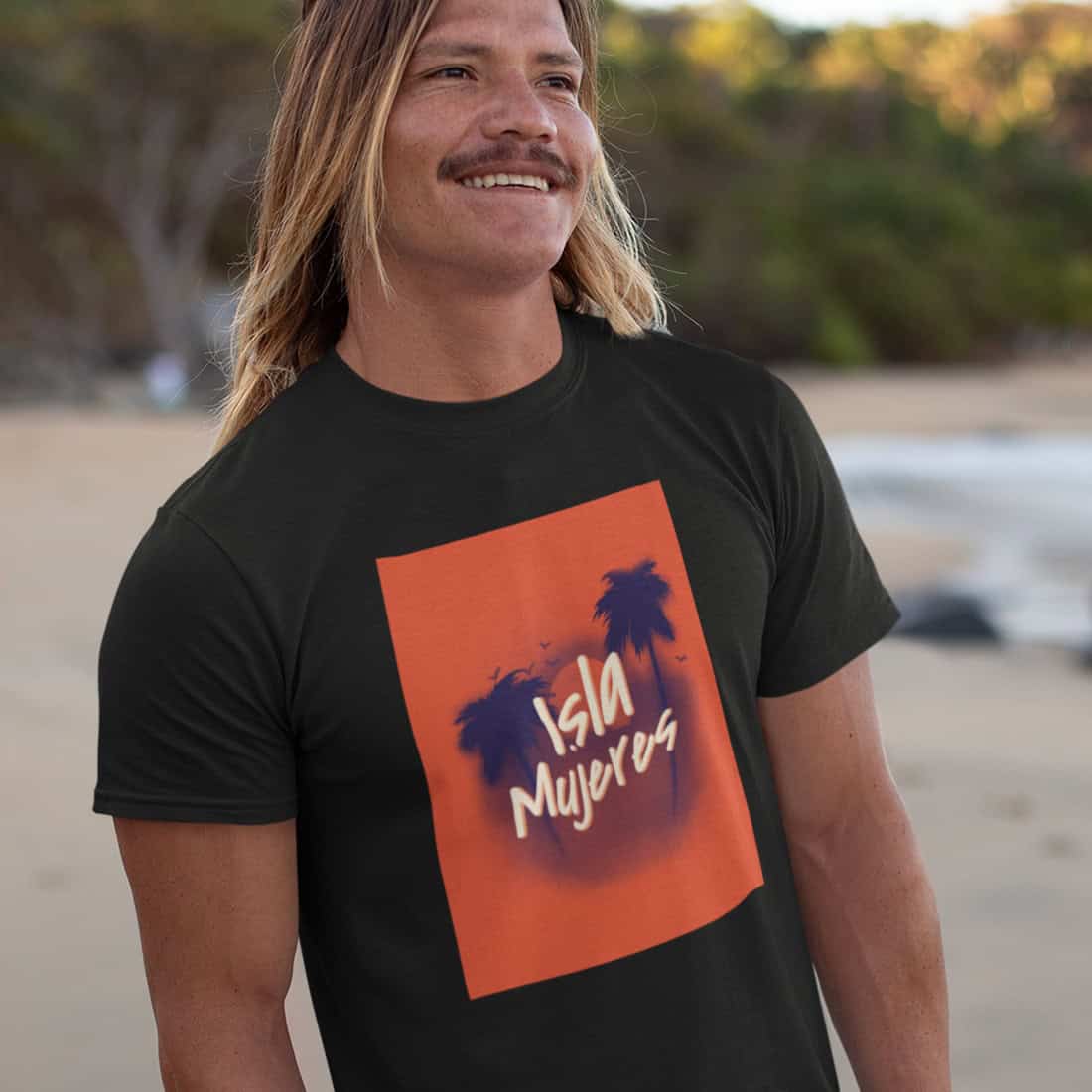 Mann mit halblangen dunkelblonden Haaren vor tropischer Kulisse. Er trägt das schwarze Shirt mit dem roten Design.
