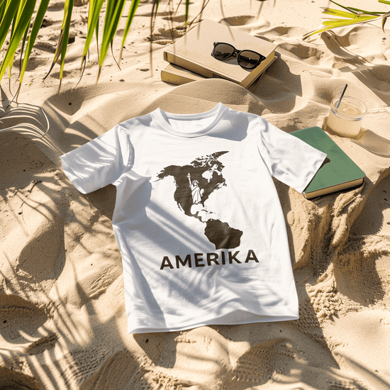 Vorschaubild der Kollektion für den Kontinent AMERIKA. Weißes T-Shirt im Sand mit Name des Kontinents.
