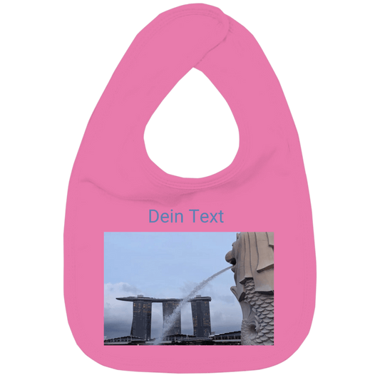 Weisses Lätzchen mit rechteckickem individuellem Foto und kurzem Text. Hier im Bild: Singapur. Merlion und MBS.