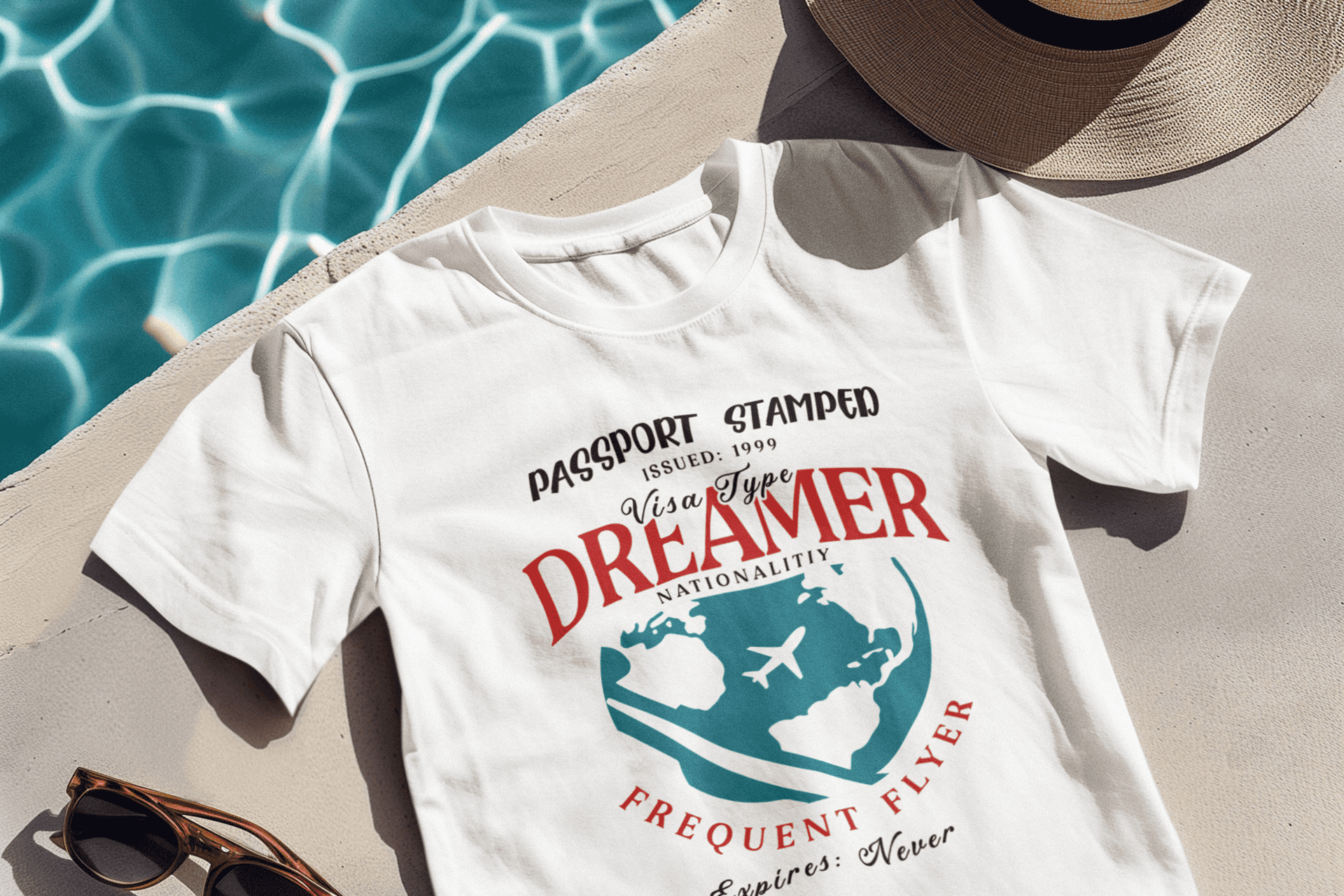 Weisses T-Shirt mit DREAMER Design, Sonnenhut und Sonnenbrilla an Pool.